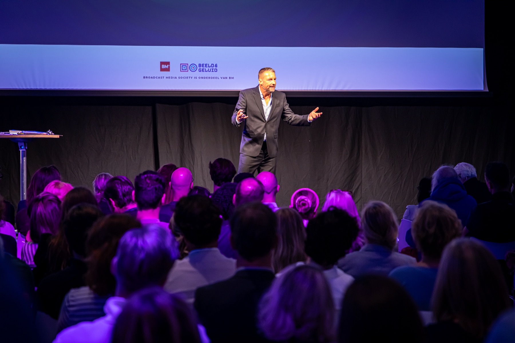 Matthias Scholten op het podium voor een volle zaal